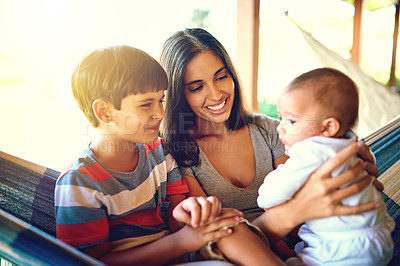 Buy stock photo Shot of a cheerful mother relaxing on a hammock with her two little boys outside at home during the day