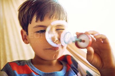 Buy stock photo Shot of a curious little boy holding up and looking through a bubble he just blew outside during the day