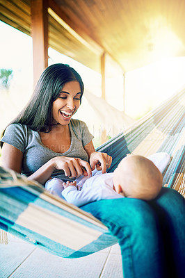 Buy stock photo Shot of a cheerful young mother relaxing on a hammock with her infant son outside at home during the day