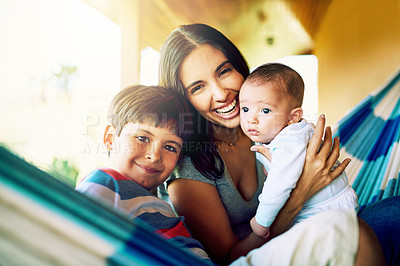 Buy stock photo Portrait of a cheerful mother relaxing on a hammock with her two little boys outside at home during the day
