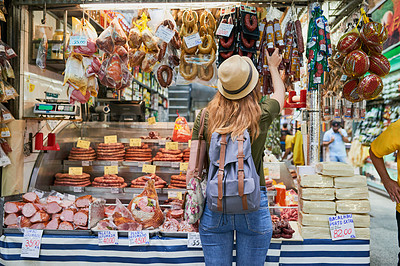Buy stock photo Rearview shot of an unrecognizable woman standing next to a market stall while browsing through the items on display