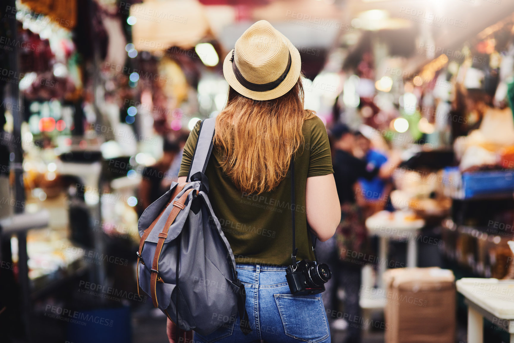 Buy stock photo Rearview shot of an unrecognizable woman wearing a hat and walking through a busy market outside during the day