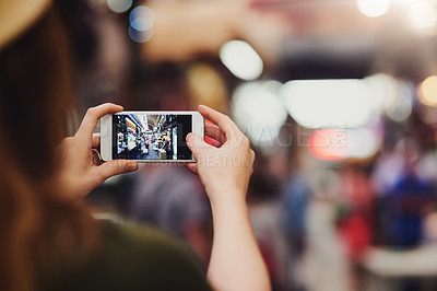Buy stock photo Over the shoulder shot of an unrecognizable woman taking photos at a busy market outside during the day