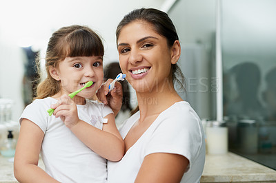 Buy stock photo Portrait of a mother and daughter brushing their teeth together in the bathroom at home