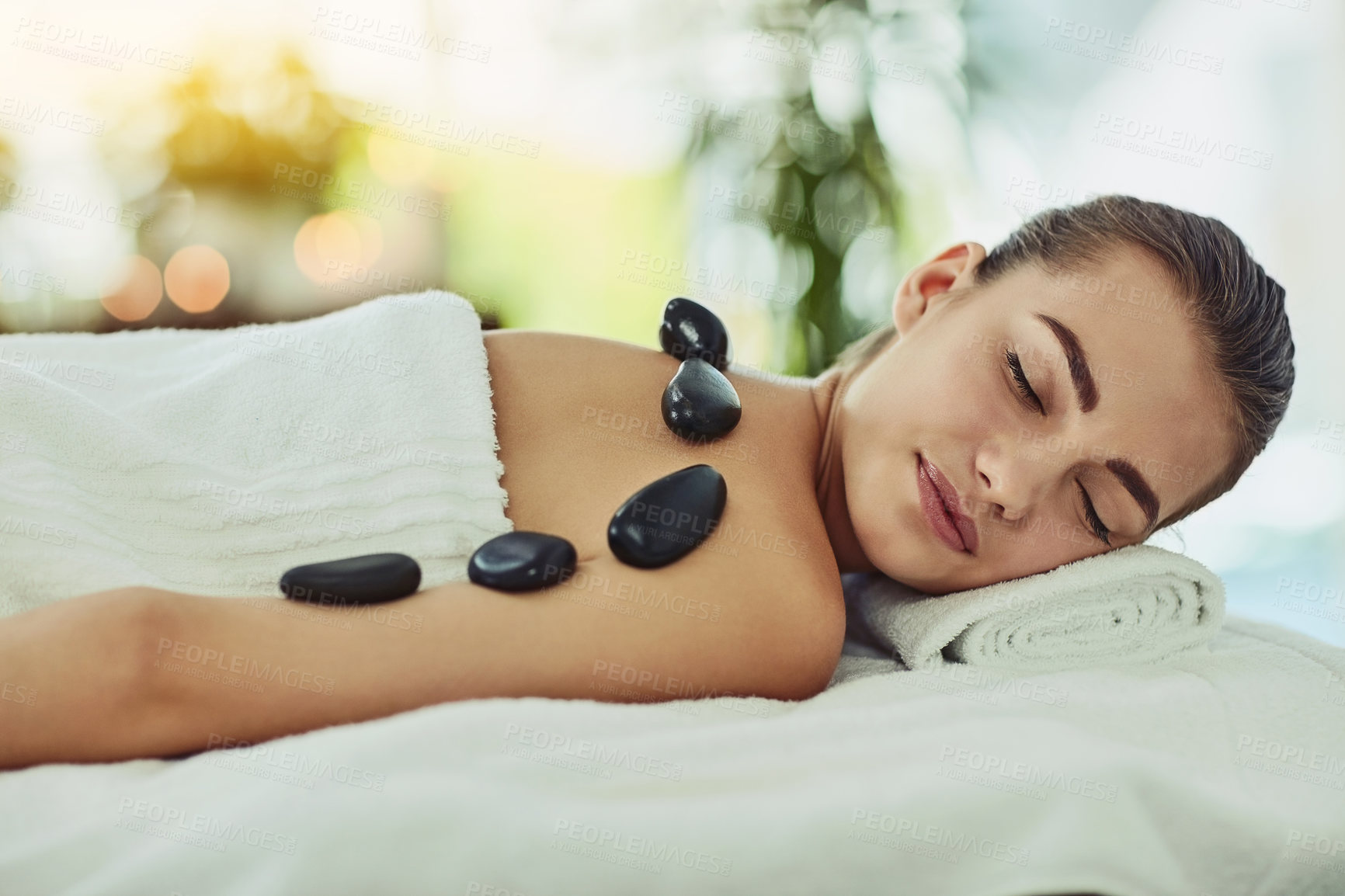 Buy stock photo Relax, woman and hot stone massage in spa for peace, calm and pain relief. Rocks, back and person at beauty salon for wellness treatment, body therapy and resting for healthy detox with eyes closed