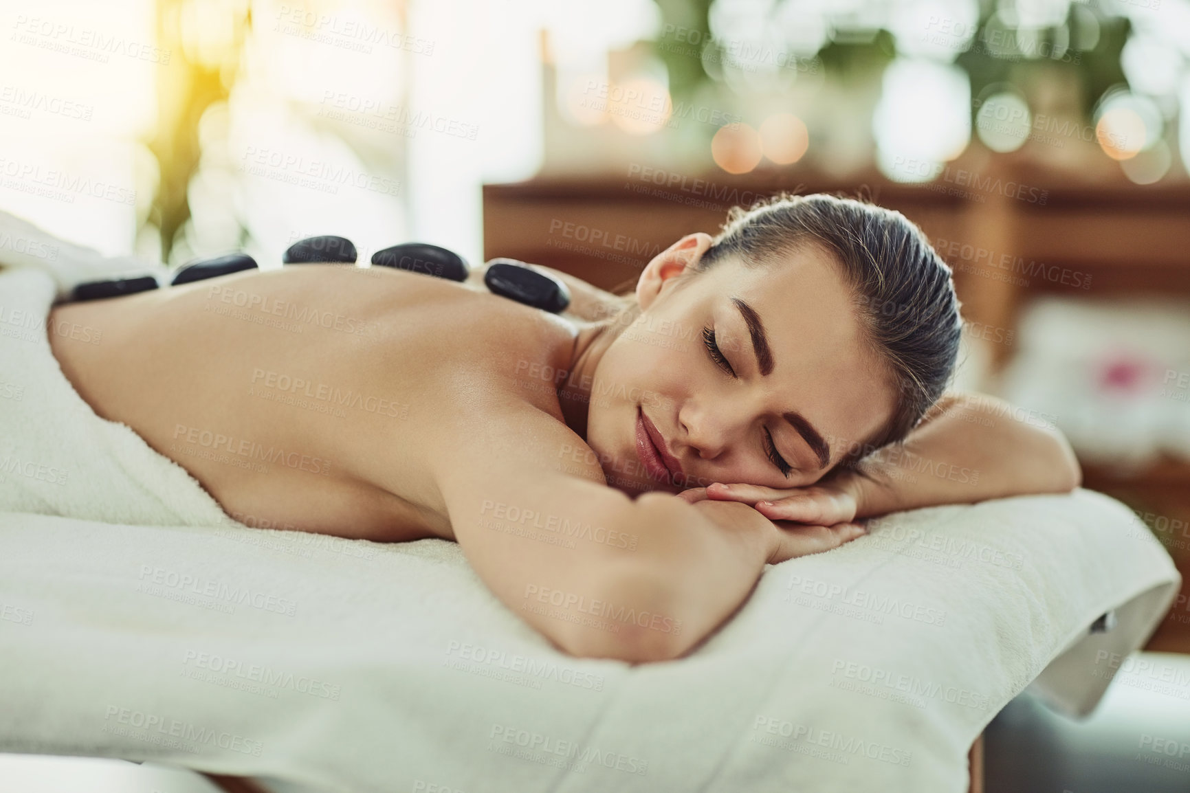 Buy stock photo Shot of an attractive young woman getting a hot stone massage at a beauty spa