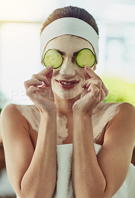 Buy stock photo Shot of an attractive young woman holding cucumber slices in front of her eyes