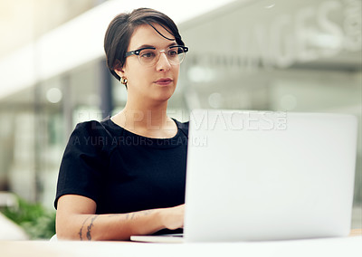 Buy stock photo Shot of an attractive young businesswoman working on a laptop in an office