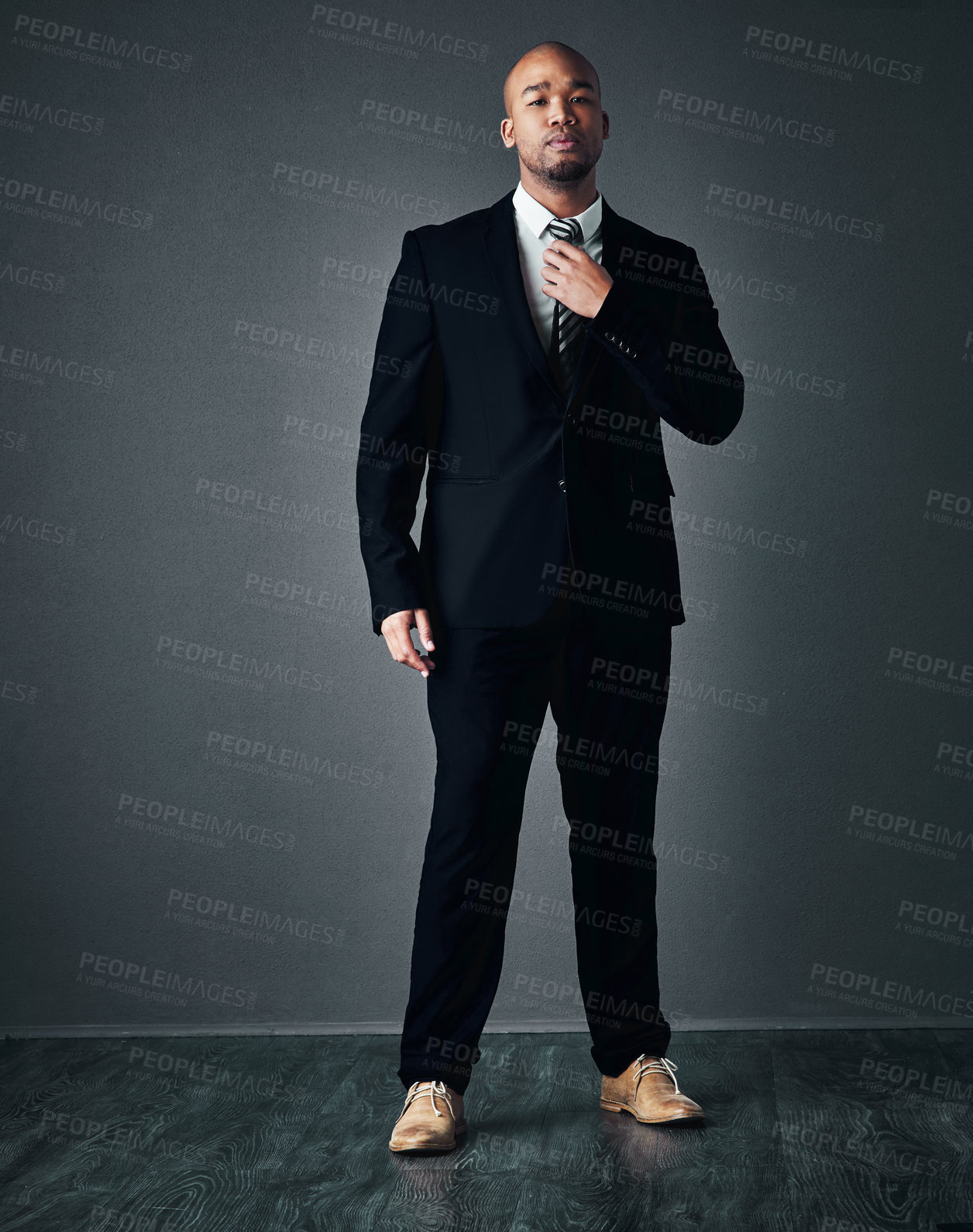 Buy stock photo Studio shot of a handsome young businessman adjusting his tie against a gray background