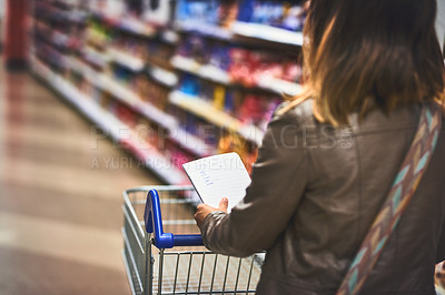 Buy stock photo Cropped shot of a woman shopping with a list in a grocery store