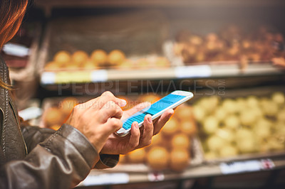 Buy stock photo Cropped shot of a woman using a mobile phone in a grocery store