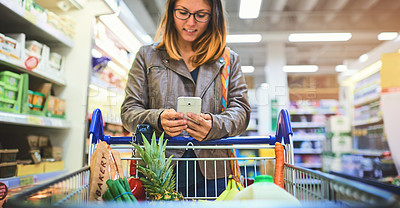 Buy stock photo Trolley, shopping and woman with phone in store for healthy food, website and reading information. Happy, person and customer with tech in supermarket for grocery list, items and checking ingredients