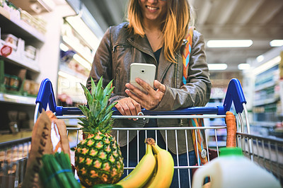 Buy stock photo Woman, phone and aisle of supermarket for shopping, digital coupon and merchandise deal. Female person, sale and store for options on offer, retail trolley and customer check online app for price