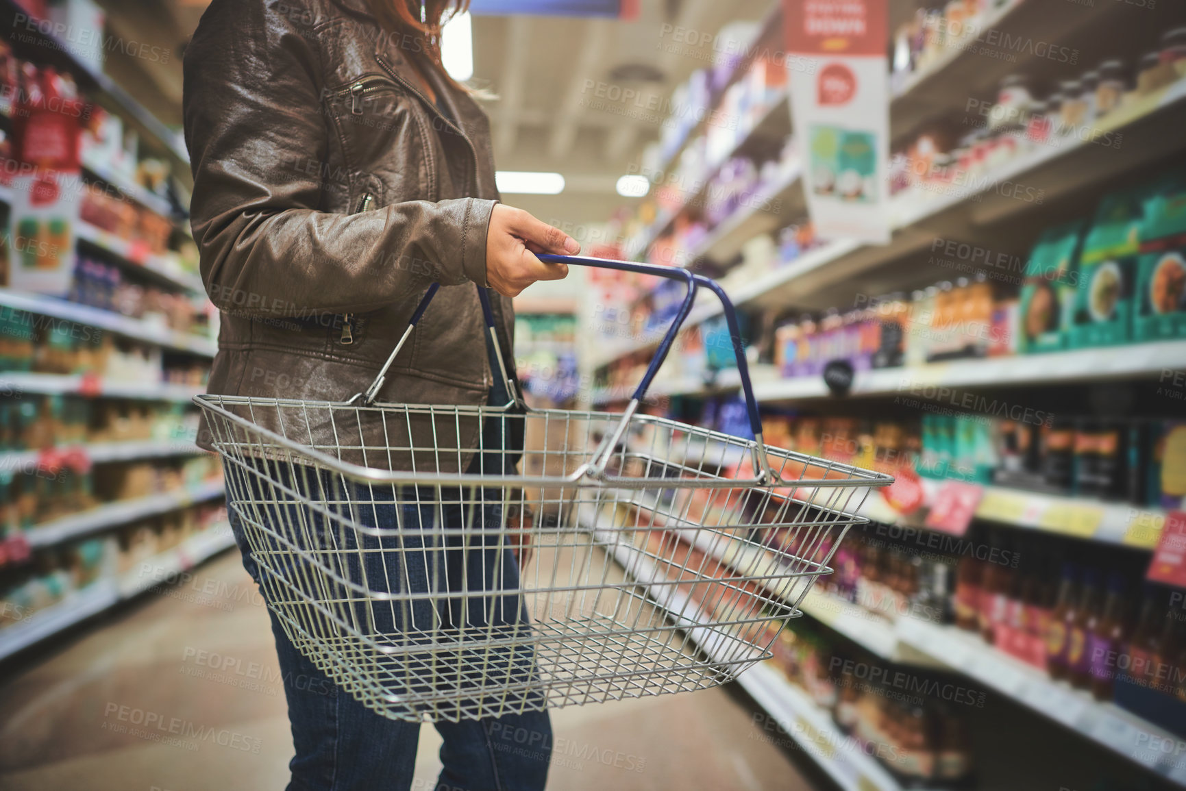 Buy stock photo Woman, basket and hands of customer in grocery store, goods discount and shelves for deal. Female person, sale and shop for options on offer, retail purchase and browsing supermarket shelf in aisle