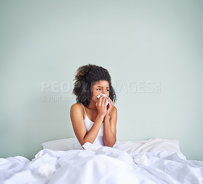 Buy stock photo Shot of a uncomfortable looking young woman holding her nose with a tissue after waking up from sleeping in her bed