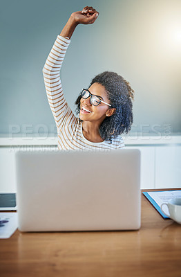 Buy stock photo Shot of a young woman doing a fist pump while working on a laptop at home