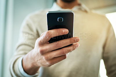 Buy stock photo Closeup shot of an unrecognizable man texting on his phone while standing in the office during the day