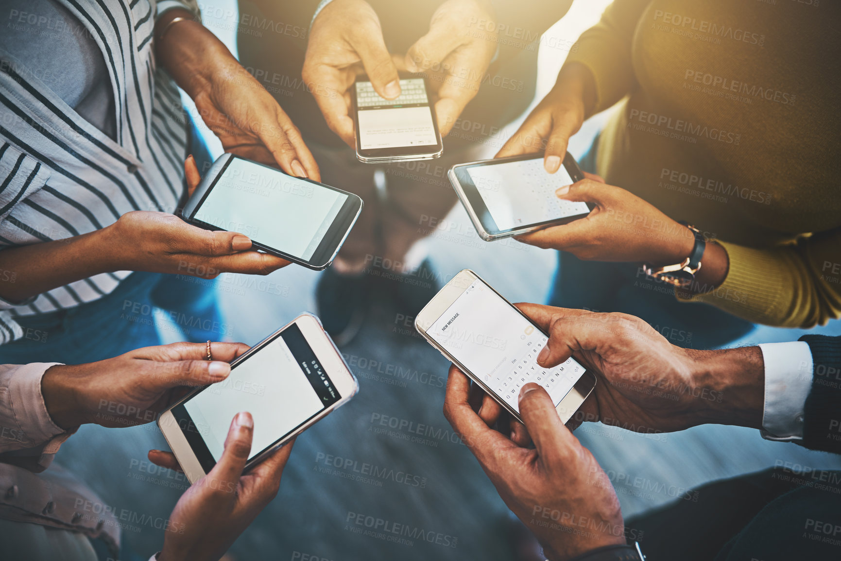 Buy stock photo Closeup shot of an unrecognizable group of businesspeople using their cellphones in synchronicity