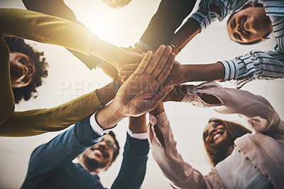 Buy stock photo Low angle shot of a group of businesspeople joining their hands together in a huddle