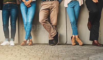 Buy stock photo Low angle shot of a group of unrecognizable people standing next to each other against a wall outside during the day