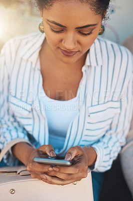 Buy stock photo Shot of a focused young woman texting on his cellphone while being seated outside during the day