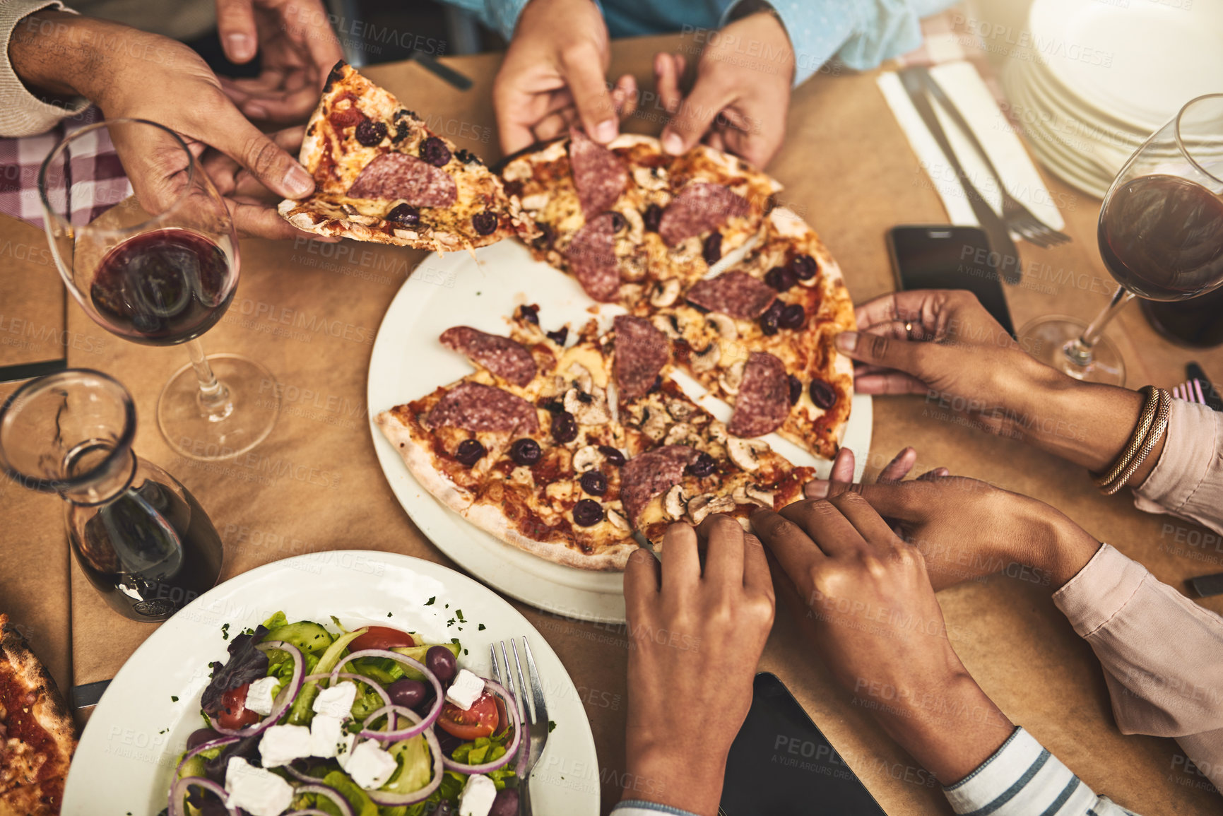 Buy stock photo High angle shot of a group of unrecognizable people's hands each grabbing a slice of pizza while being seated at a restaurant