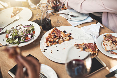 Buy stock photo Shot of a group of unrecognizable people eating pizza together while being seated at a table inside of a restaurant