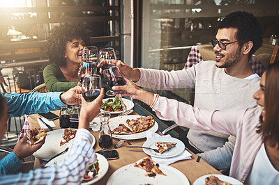Buy stock photo Shot of a group of cheerful young friends having a celebratory toast with wine at dinner inside of a restaurant