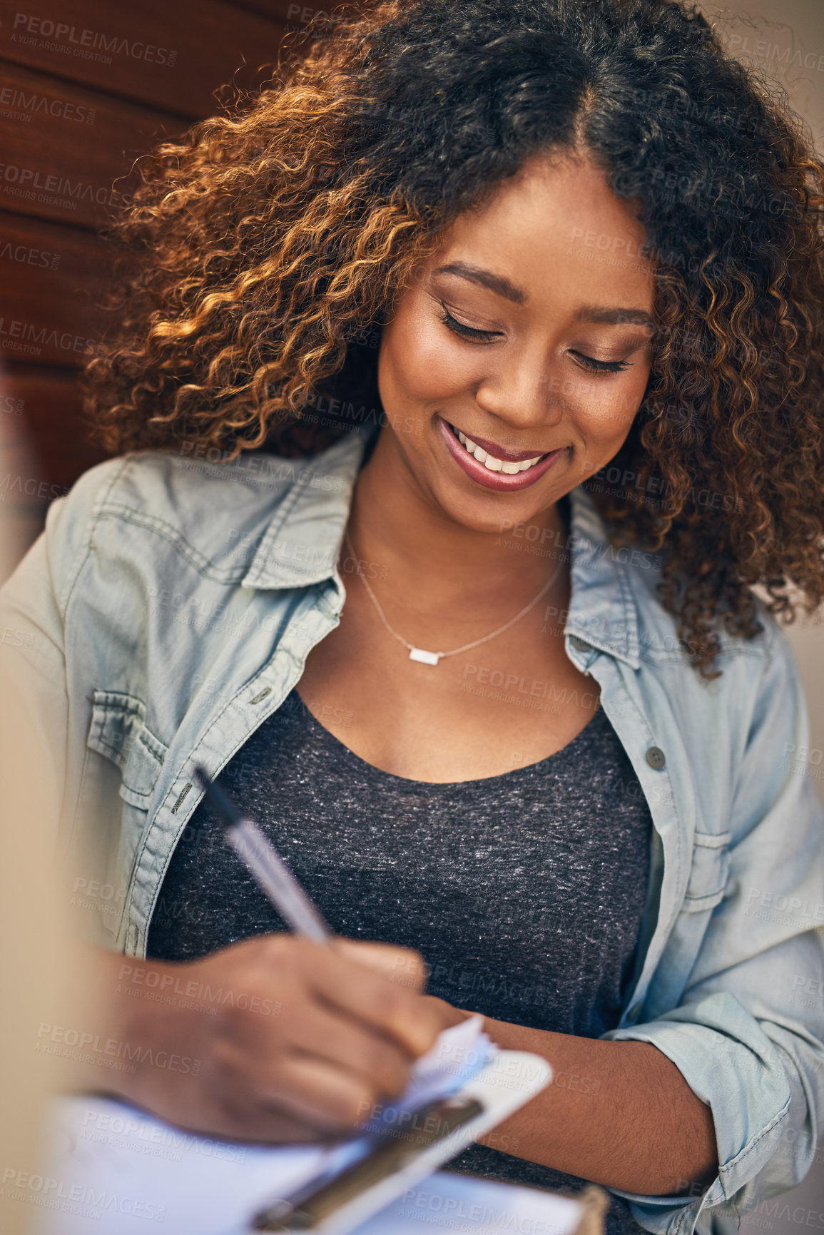 Buy stock photo Shot of a young woman signing for her delivery from the courier