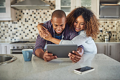 Buy stock photo Cropped shot of an affectionate young couple using a tablet in their kitchen at home