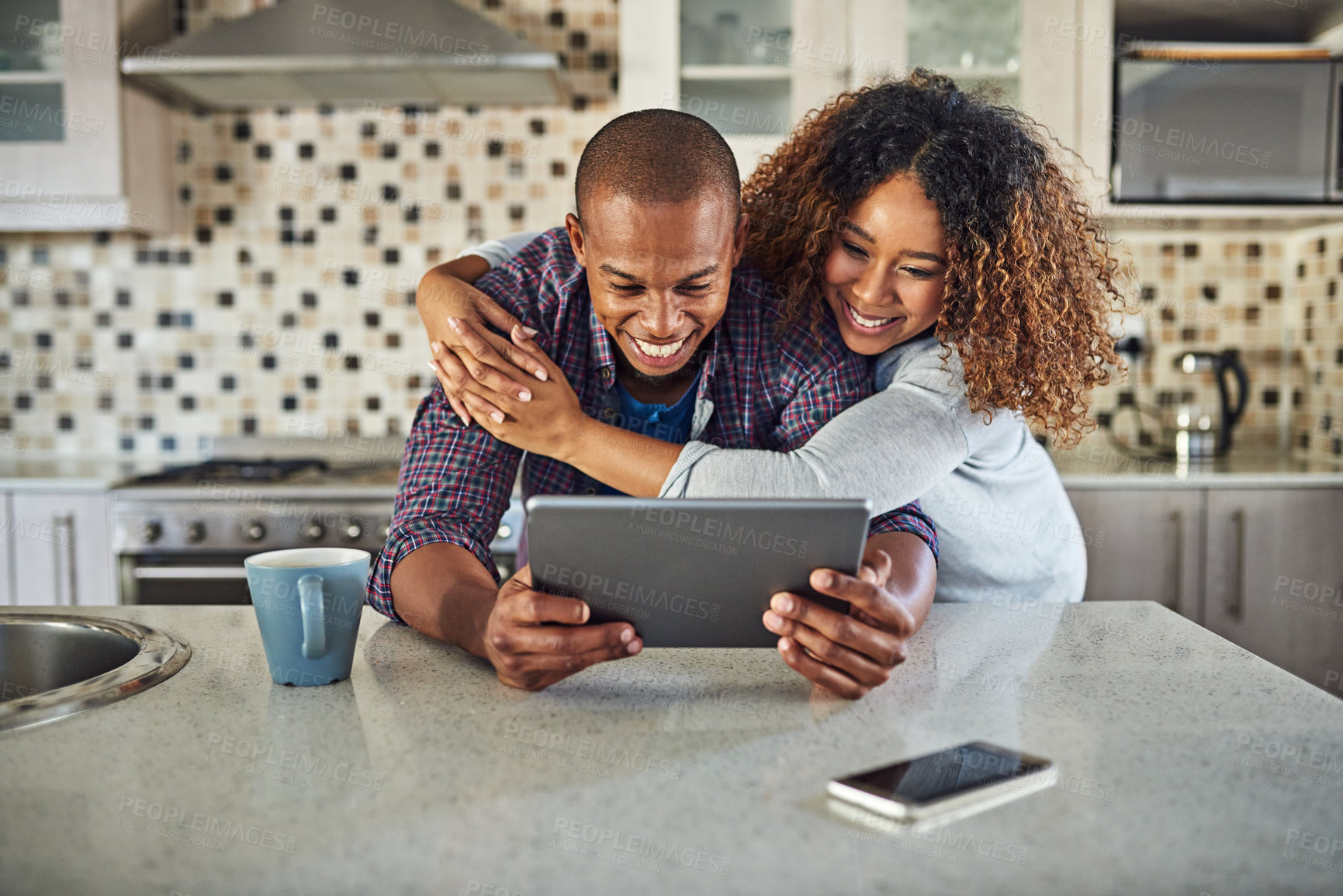 Buy stock photo Cropped shot of an affectionate young couple using a tablet in their kitchen at home