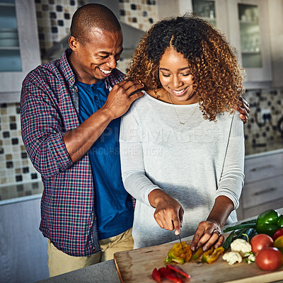 Buy stock photo Cropped shot of an attractive young woman cooking at home while her husband keeps her company