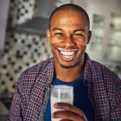 Buy stock photo Cropped portrait of a handsome young man drinking a glass of milk in the kitchen at home