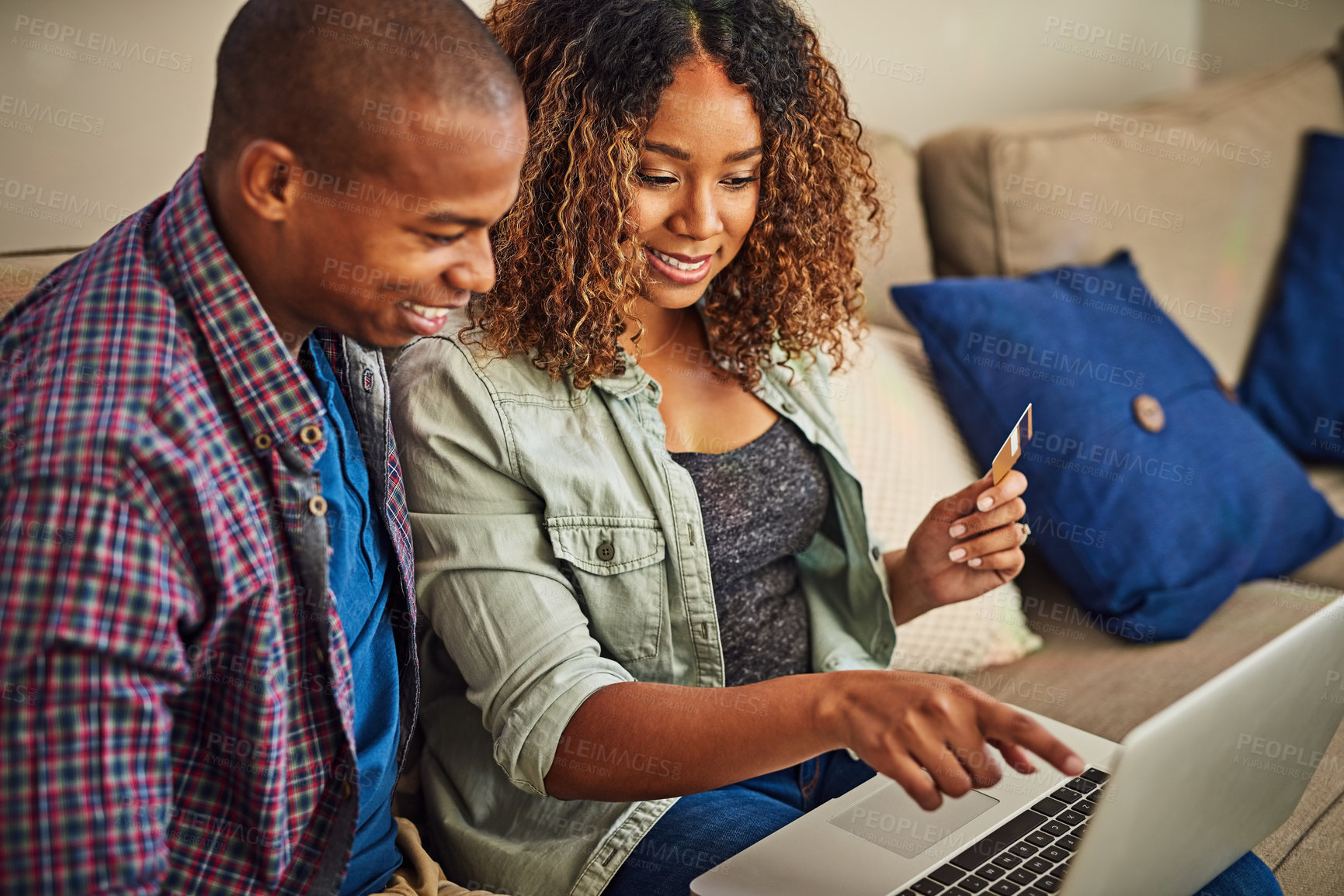 Buy stock photo Shot of a cheerful young couple doing online shopping together while being seated on a couch at home