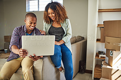 Buy stock photo Shot of a cheerful young couple doing online shopping together while being seated on a couch at home