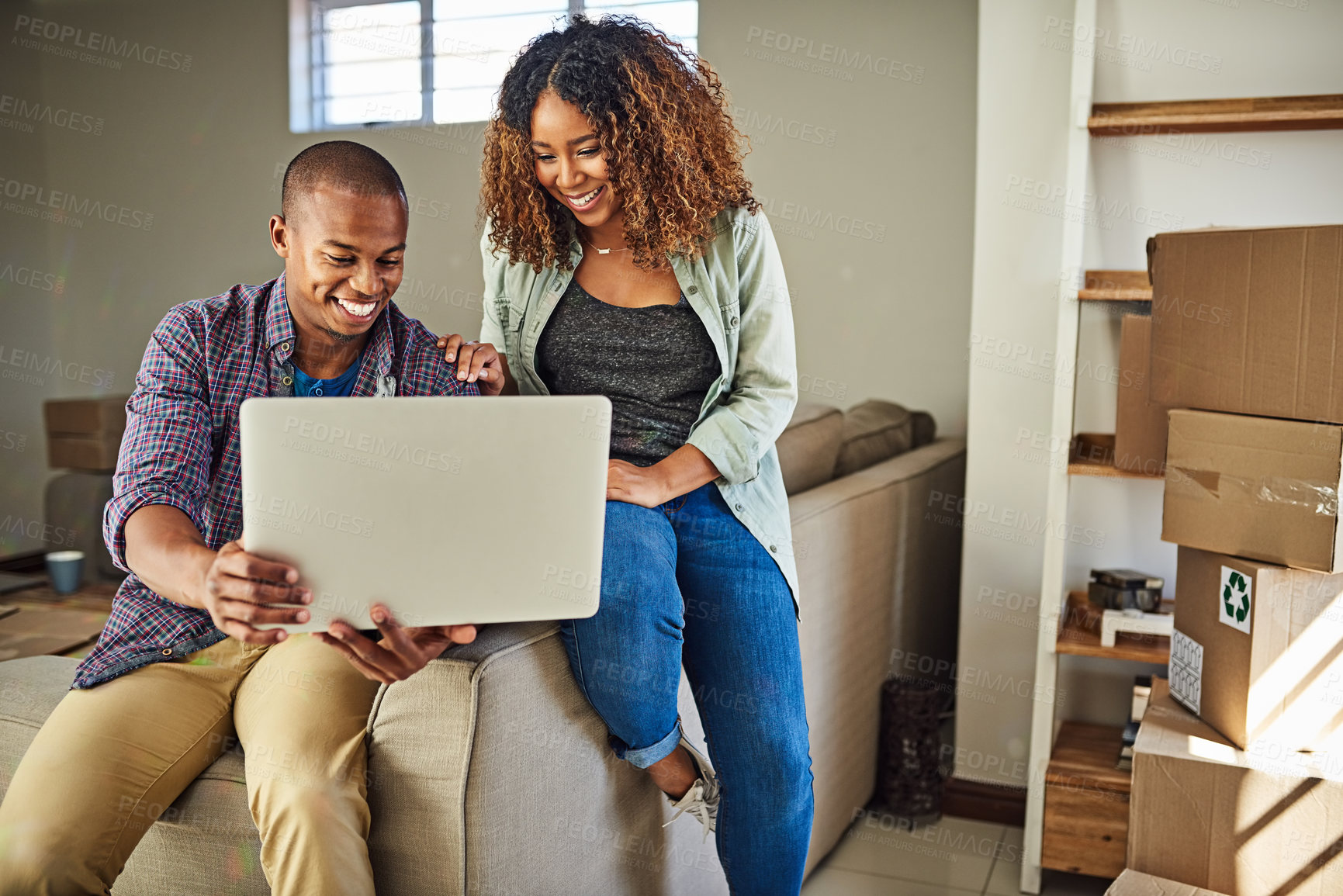 Buy stock photo Shot of a cheerful young couple doing online shopping together while being seated on a couch at home