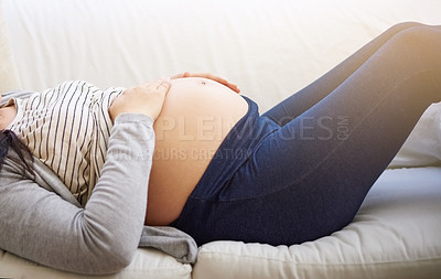 Buy stock photo Cropped shot of an unrecognizable young pregnant woman relaxing on the sofa at home