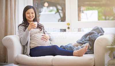 Buy stock photo Portrait of an attractive young pregnant woman drinking an iced coffee while relaxing on the sofa at home