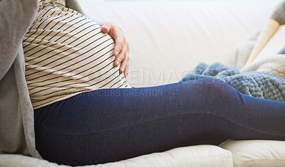 Buy stock photo Cropped shot of an unrecognizable young pregnant woman relaxing on the sofa at home