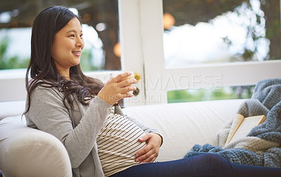 Buy stock photo Shot of an attractive young pregnant woman drinking an iced coffee while relaxing on the sofa at home