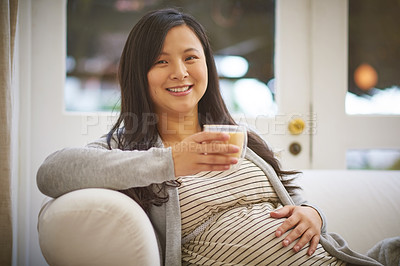 Buy stock photo Portrait of an attractive young pregnant woman drinking an iced coffee while relaxing on the sofa at home