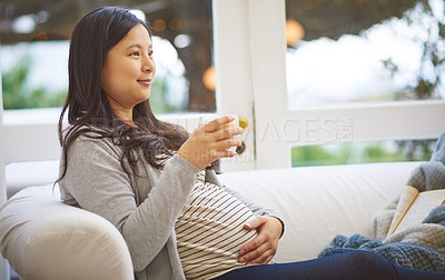 Buy stock photo Shot of an attractive young pregnant woman drinking an iced coffee while relaxing on the sofa at home