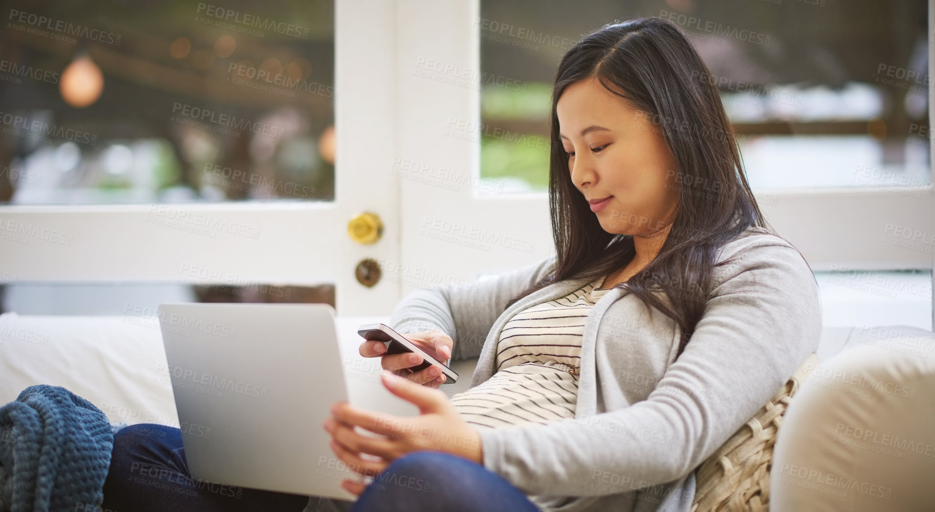 Buy stock photo Shot of a pregnant woman using a laptop and cellphone at home