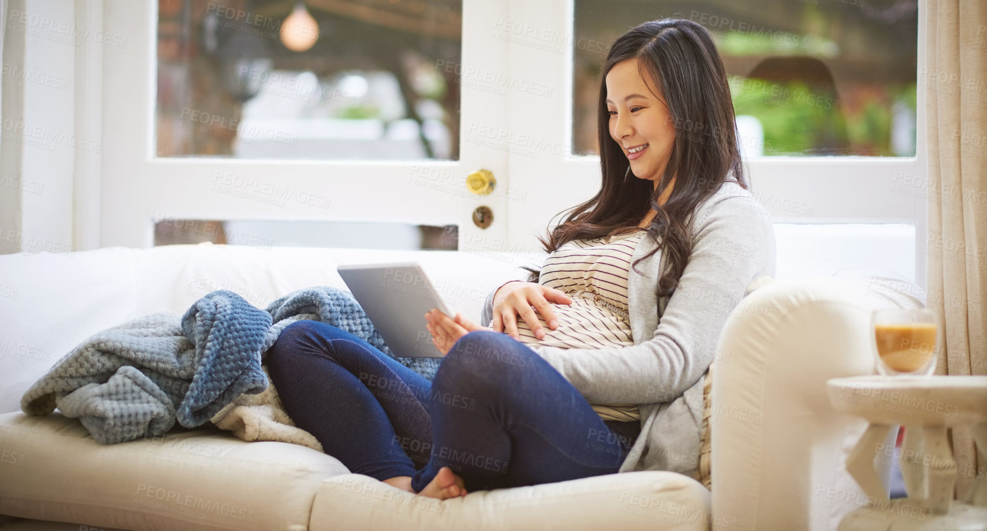 Buy stock photo Shot of a pregnant woman using a digital tablet at home