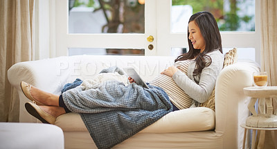 Buy stock photo Shot of a pregnant woman using a digital tablet at home