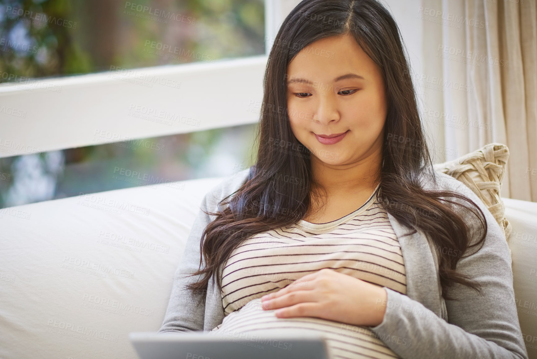 Buy stock photo Shot of a pregnant woman using a digital tablet at home