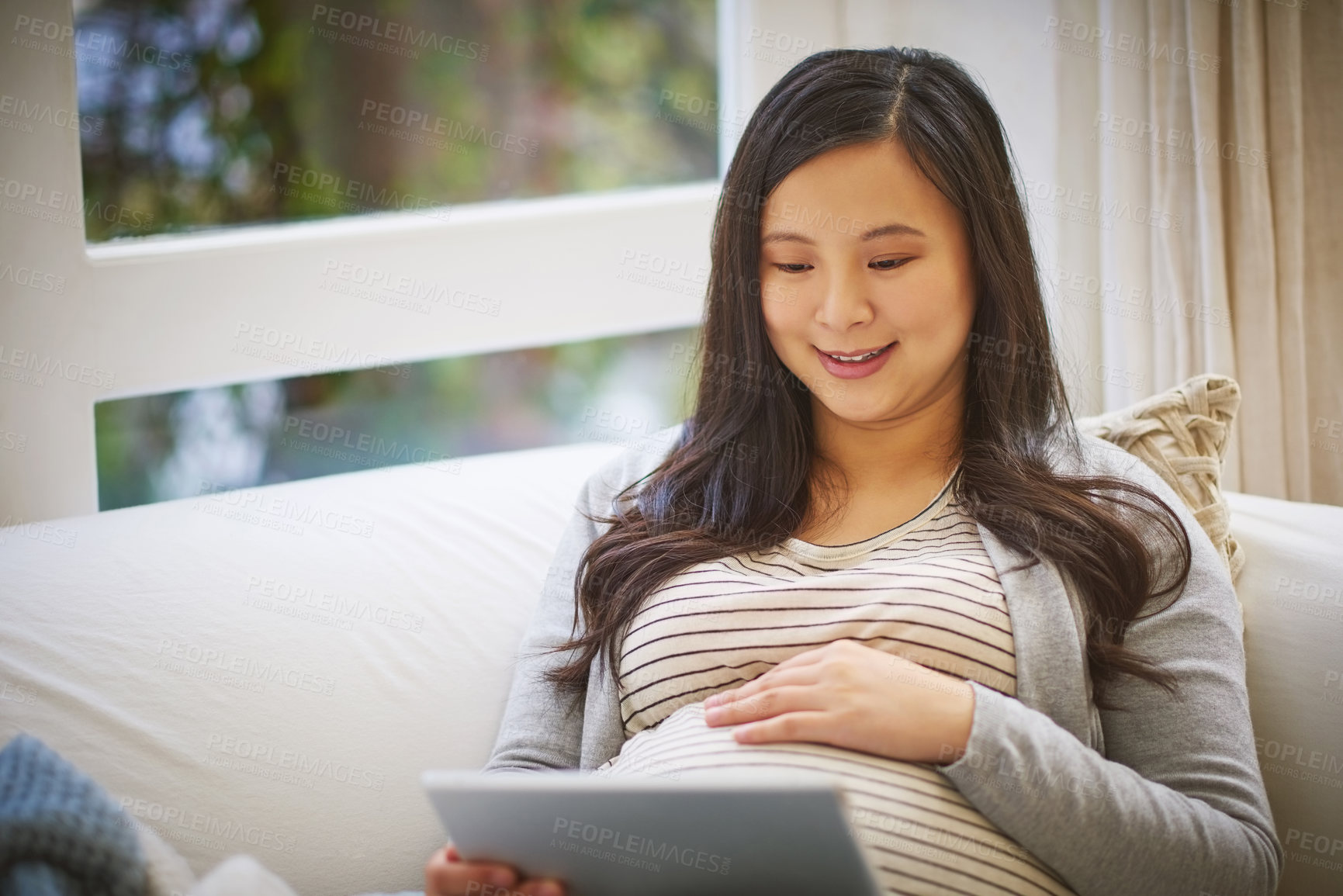 Buy stock photo Shot of a pregnant woman using a digital tablet at home