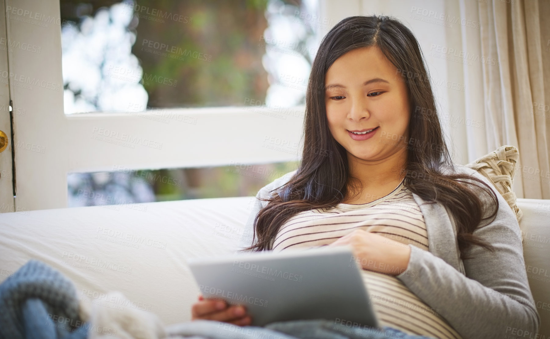 Buy stock photo Shot of a pregnant woman using a digital tablet at home