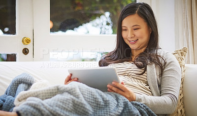 Buy stock photo Shot of a pregnant woman using a digital tablet at home