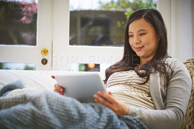 Buy stock photo Shot of a pregnant woman using a digital tablet at home